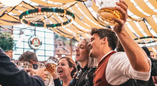 Allegra compagnia brinda con boccali di birra, festeggiando l'Oktoberfest. Litri di birra scorrono in un'atmosfera di gioia.