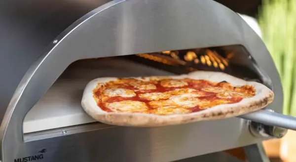 En pizza med tomatsås och ost bakas i en ugn på en pizzasten eller pizzastål.