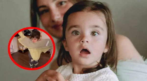 Dziecko z pomocą mamy uczy się, jak założyć kurtkę. Mama z uśmiechem obserwuje malucha.