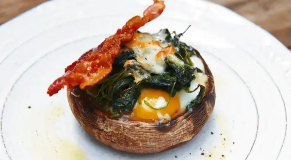 Gefüllter Portobello Pilz mit Ei, Spinat und Käse, garniert mit knusprigem Speck. Ein einfaches und leckeres Portobello Pilz Rezept.