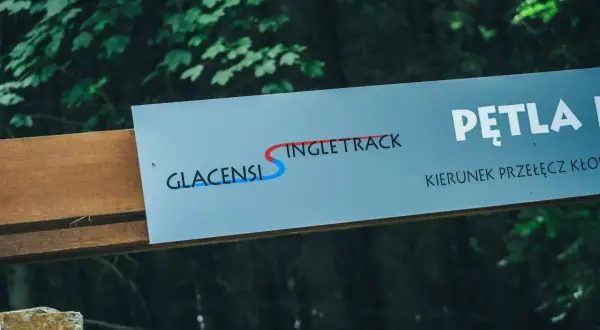 Tablica informacyjna z napisem "GLACENSIS SINGLETRACK" i strzałką wskazującą kierunek.