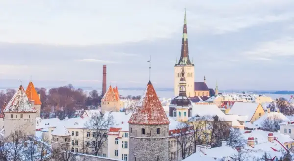 Zimowy widok na średniowieczne wieże i dachy pokryte śniegiem w Tallinnie, stolicy Estonii.