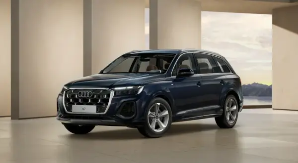 Eleganckie, ciemnogranatowe nowe Audi Q7 prezentuje się na tle nowoczesnej architektury i malowniczego krajobrazu.