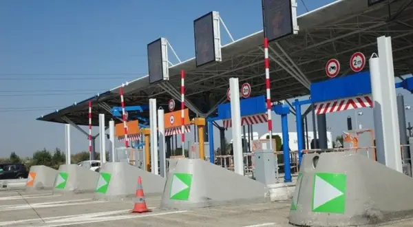 Voies de péage avec des indicateurs verts et orange. Une voie semble réservée au péage gratuit pour les handicapés.