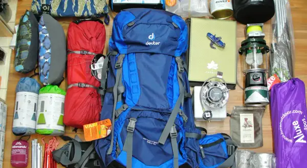 Alles, was man braucht für Camping: Rucksack, Schlafsäcke, Isomatten, Kocher, Lampe, Zeltstangen, Tasse und mehr.