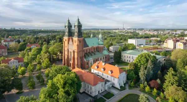 Widok na Ostrów Tumski z dominującą katedrą. Wokół zieleń drzew i zabudowania miejskie.