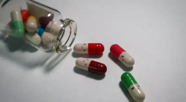Kolorowe kapsułki z uśmiechniętymi buźkami, niektóre wypadły z buteleczki. Czy psychotropy to narkotyki?