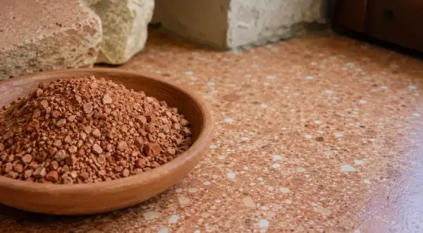Ciotola di terra rossa, materiale grezzo per il rinzaffo significato. Sotto blocchi di pietra e un pavimento in graniglia.
