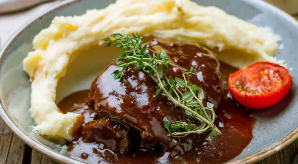 Schab w sosie własnym, podany z purée ziemniaczanym i pieczonym pomidorkiem. Aromatyczny, domowy obiad.