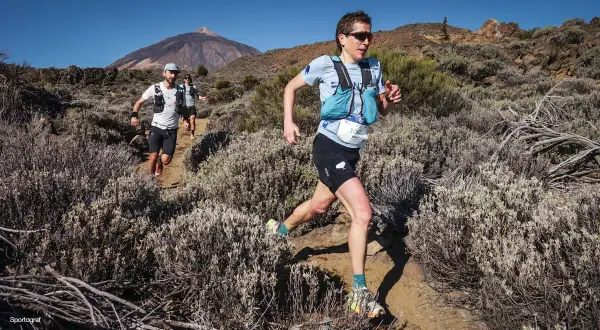 Coureurs en plein effort sur un sentier rocailleux, le Teide en arrière-plan, lors du **Tenerife Bluetrail**.