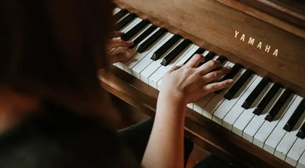 Dłonie na klawiaturze pianina Yamaha. Rozpoczyna się nauka gry na pianinie online, odkrywanie melodii.