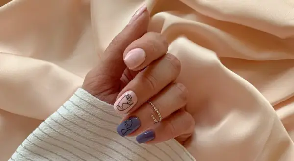 Manicure con disegno minimalista di un volto su unghie rosa e viola. Scopri cos'è la dry manicure per unghie perfette.