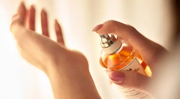 Dłoń rozpyla perfumy, tworząc subtelne stężenie zapachu.