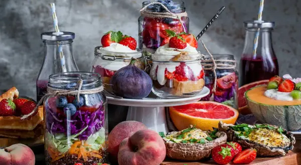 Färgglada burkar med frukt och grönsaker, perfekta för ett somrigt brunch recept. Jordgubbar, blåbär, kål och quinoa i lager.