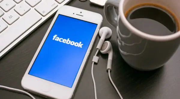 Telefon z Facebookiem, klawiatura i kawa. Dowiedz się, jak założyć konto szkoły na Facebooku, by być bliżej uczniów.