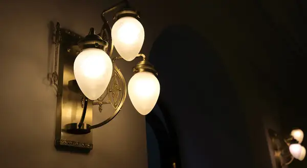 Elegancki kinkiet z trzema mlecznymi kloszami, rzucający ciepłe światło. Trudno ocenić ile lumenów na m2, ale tworzy przytulną atmosferę.