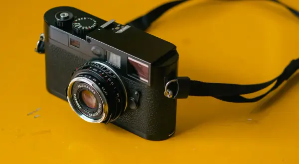 A black camera with a Voigtlander Color Skopar 35mm lens sits on a yellow surface.