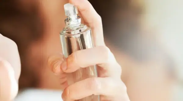 Eine Hand hält einen Glasflakon, bereit, einen selbstgemachten Erfrischungsspray aufzusprühen.