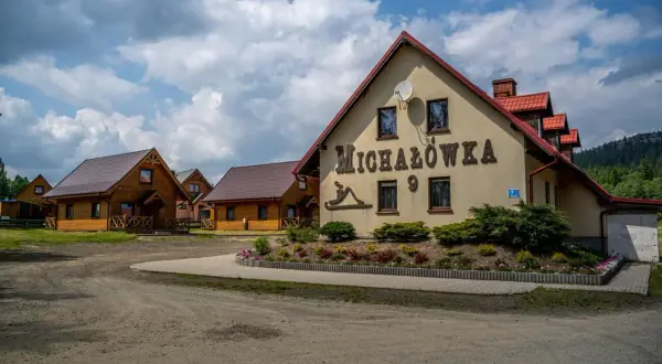 Ośrodek jazdy konnej Michałówka z drewnianymi domkami i głównym budynkiem z napisem "Michałówka".