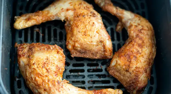 Trozos de pollo dorados y jugosos en la freidora de aire, listos para disfrutar.