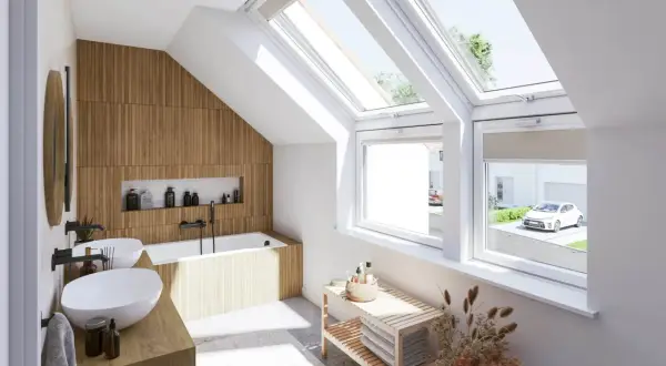 Salle de bain sous pente lumineuse avec murs en bois, baignoire, double vasque et grandes fenêtres de toit offrant une vue sur un jardin.