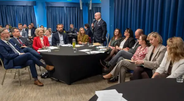 Grupa prawników siedzi przy okrągłych stołach podczas konferencji w Krakowie.