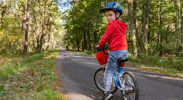Chłopiec w kasku na rowerze na leśnej trasie rowerowej w Niepołomicach.