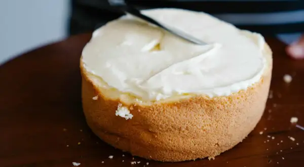Bizcocho esponjoso cubierto con glaseado blanco cremoso, listo para decorar. Una deliciosa receta bizcocho.