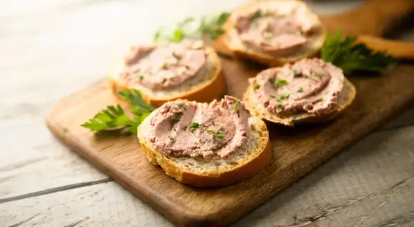 Leberwurstbrote auf Holzbrett. Vorsicht bei Leberwurst in der Schwangerschaft wegen Vitamin-A-Überdosierung.