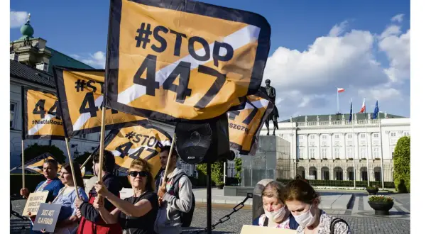 Protestujący trzymają flagi z napisem #STOP 447. Tło stanowi Pałac Prezydencki w Warszawie.