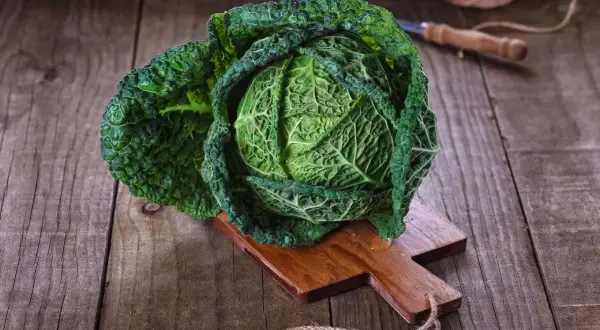 Ein frischer Wirsingkopf liegt auf einem Holzbrett, bereit für leckere Wirsing Rezepte.