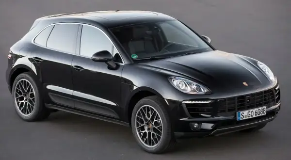Czarny Porsche Macan na ciemnym tle. Choć piękny, warto znać jego potencjalne wady przed zakupem.