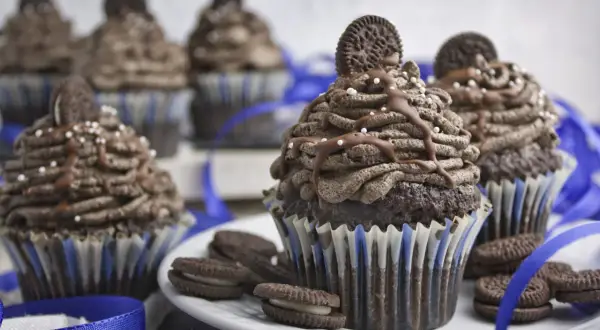 Schokoladen-Muffins mit Oreo-Creme-Topping, garniert mit ganzen Oreos und Schokoladensauce. Ein Genuss für alle Oreo-Fans!