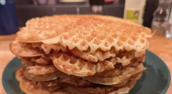 En hög med gyllene, glutenfria våfflor på en grön tallrik. Perfekt för en frukost eller fika.