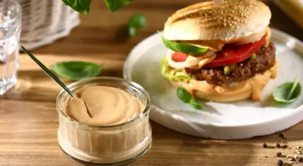 Pyszny sos do burgera w słoiczku, obok apetycznego burgera z dodatkami. Idealny do każdej kanapki.