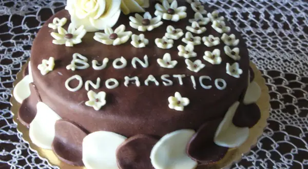 Torta al cioccolato con decorazioni in pasta di zucchero, un augurio speciale: "Buon Onomastico" per un uomo.