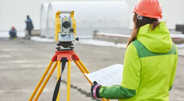 Geodetka z mapą przy tachimetrze. Czy geodeta musi powiadomić sąsiadów o pracach?