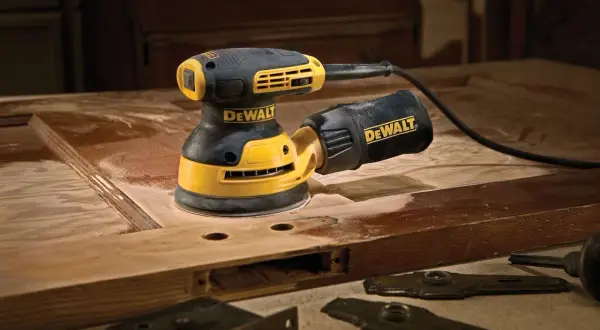 Szlifierka mimośrodowa DeWalt w akcji, pokazująca, jak działa, podczas renowacji drewnianych drzwi.