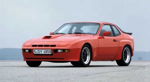 Pomarańczowy Porsche 924 Targa z lat 80. na pustej drodze.