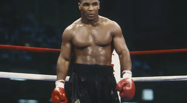 Mike Tyson in the ring, ready to fight. His intense gaze and powerful physique embody the spirit of how to fight like Mike Tyson.