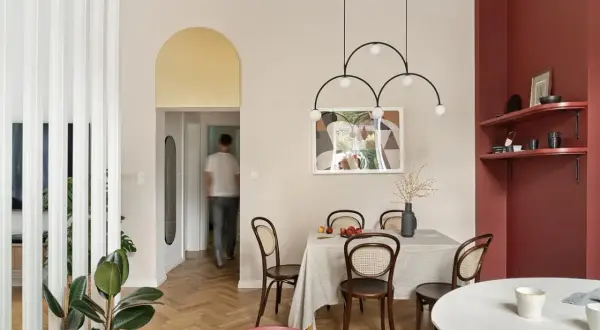 Złoty łuk nad drzwiami dodaje elegancji, a jasne ściany i drewniana podłoga tworzą przytulną atmosferę. Idealne rozwiązanie, czym wykończyć łuk w salonie.