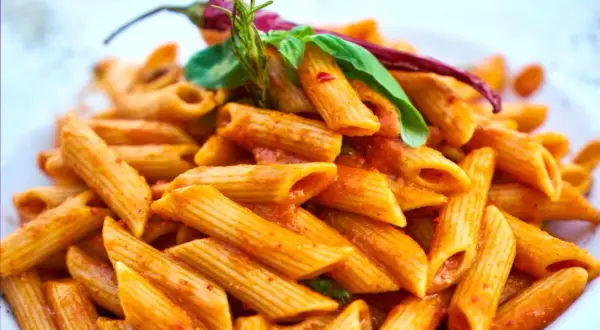 Penne w pikantnym sosie pomidorowym, ozdobione papryczką chili i bazylią. Danie wygląda jak makaron Gigi Hadid, idealne na szybki lunch.