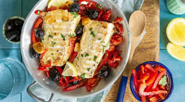 Délicieuse recette cabillaud aux poivrons rouges, olives noires et citron, servie dans un plat en métal.