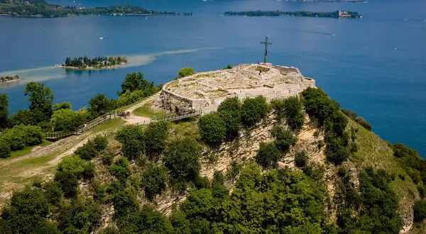 Rocca di Manerba, un sito archeologico con rovine e una croce, domina il lago.