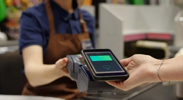 Bezahlvorgang mit Smartphone: Eine virtuelle Kreditkarte wird an einem Terminal abgerechnet.