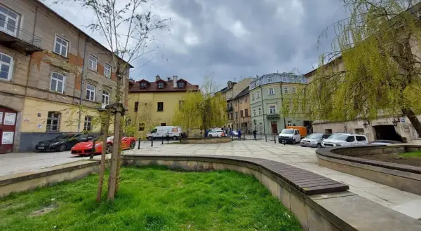 Plac rybny Lublin z kolorowymi kamienicami, zielenią i zaparkowanymi samochodami.