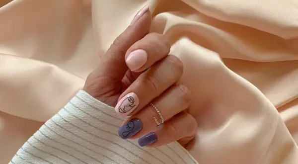 Mano con unghie curate: alcune rosa pastello, altre viola con disegni minimalisti. Un'idea per come mettere lo smalto in modo originale.