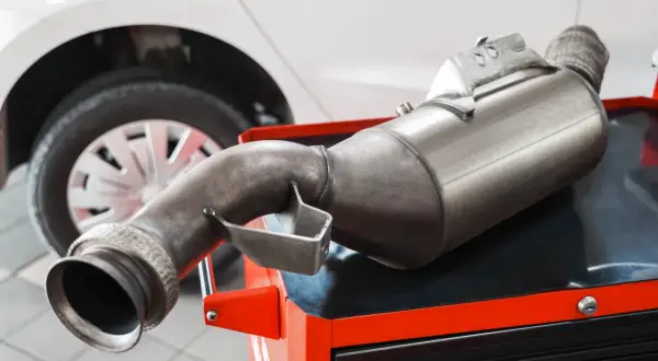 Filtr DPF na czerwonej skrzynce narzędziowej, obok koła samochodu. Zastanawiasz się, ile popiołu w dpf?