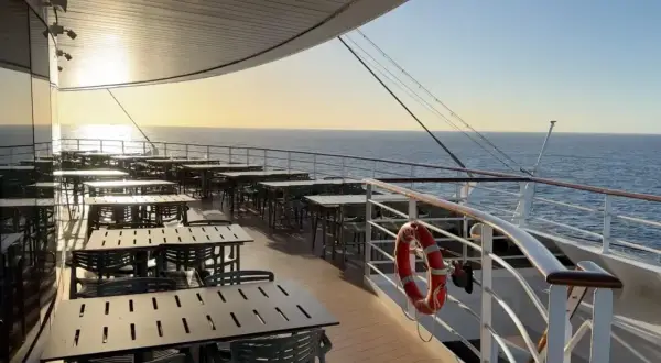 Leere Tische und Stühle auf einem Kreuzfahrtschiff-Deck bei Sonnenuntergang, bereit für die Gäste nach den marine surveys.