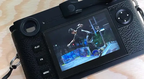 The Leica M11 displays a dynamic shot of a skateboarder mid-air at a graffiti-covered skatepark.